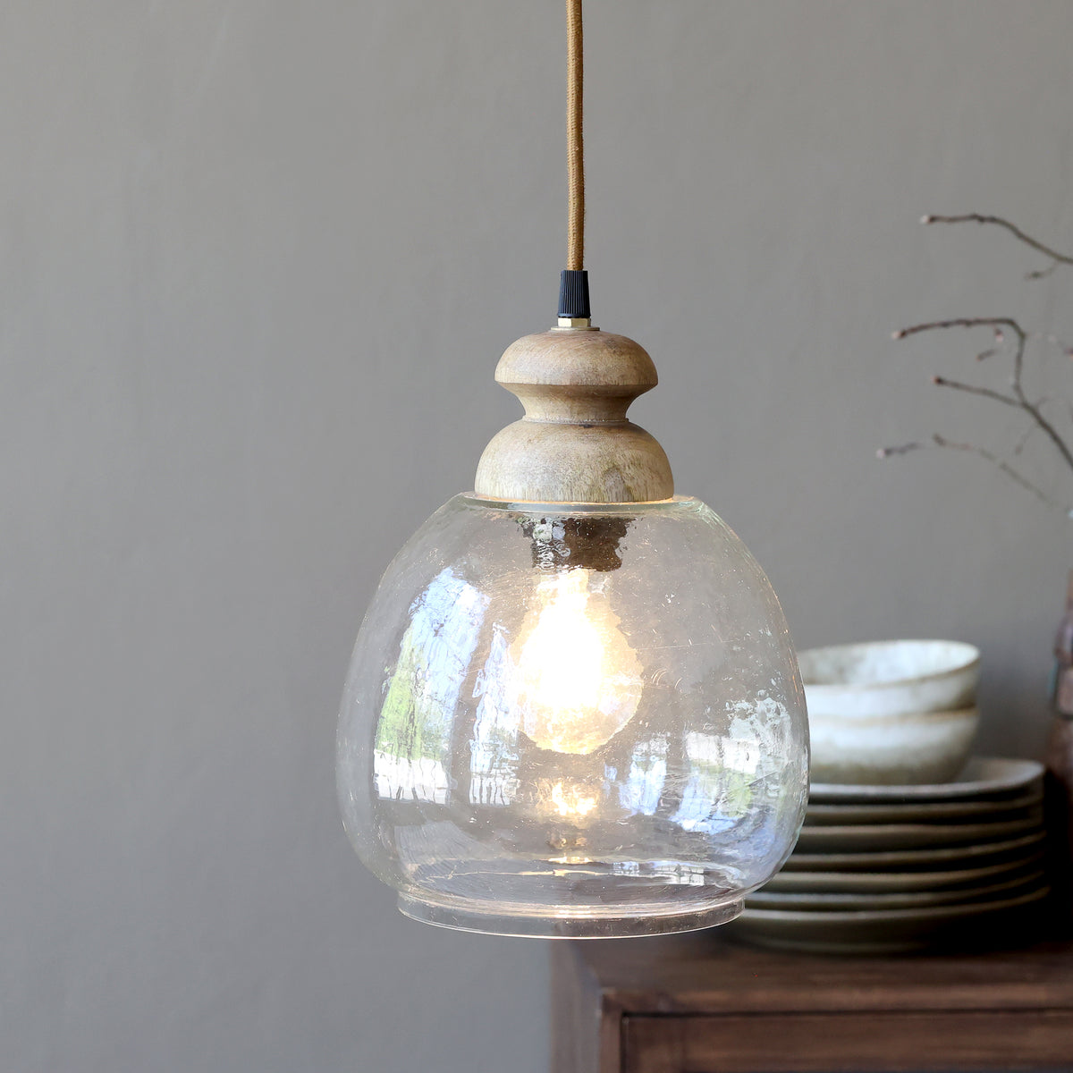 hammered glass pendant light with wooden top displayed in dining room against grey colour walls