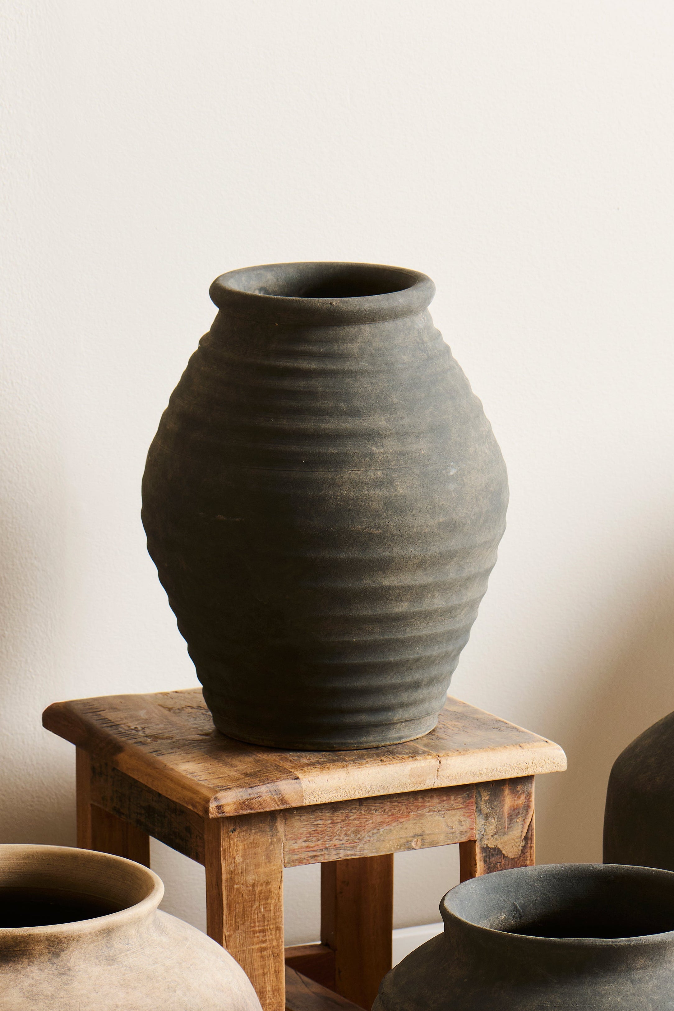 dark textured terracotta vase displayed with other terracotta vases