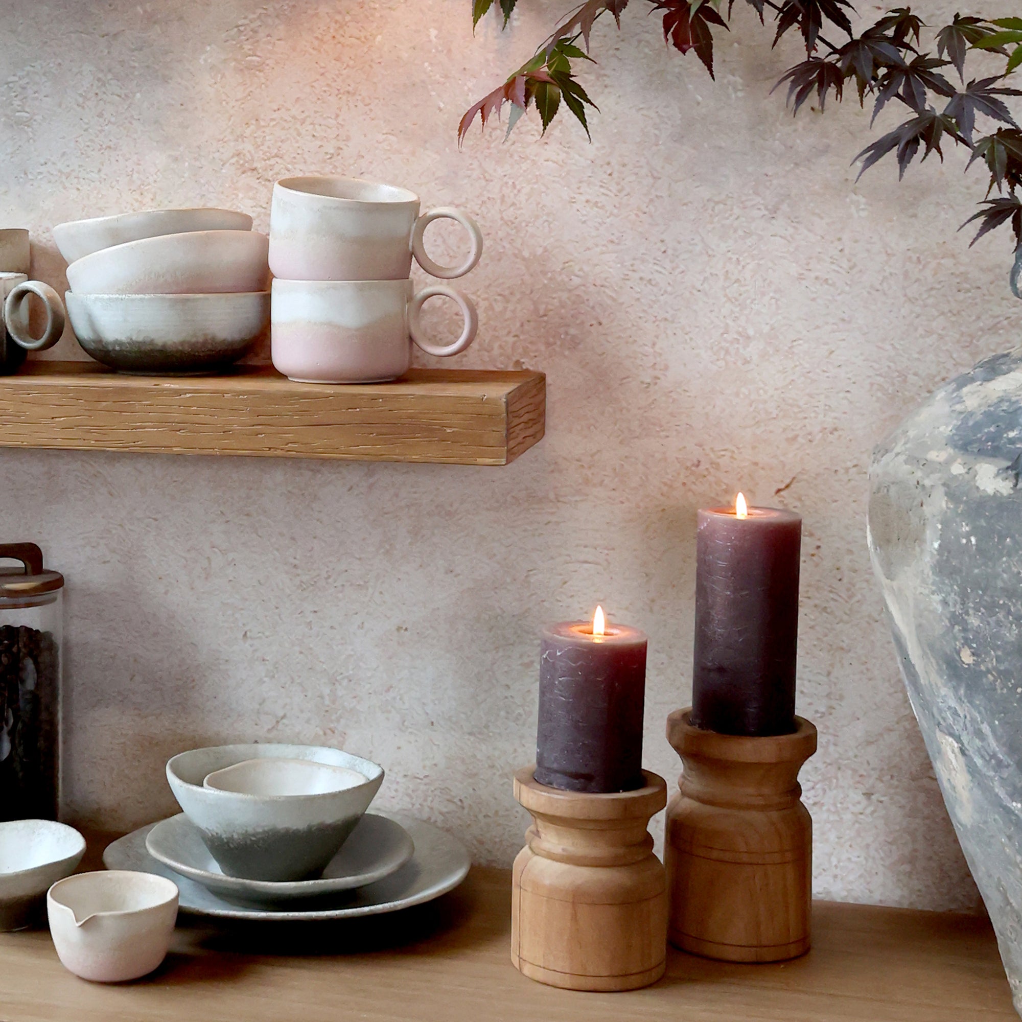 large chunky wooden candlestick displayed on wooden surface against neutral wall